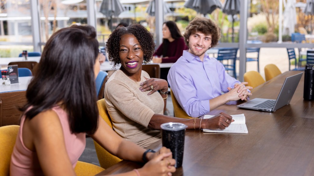 A diverse group of employees smiling and working together at a conference table.