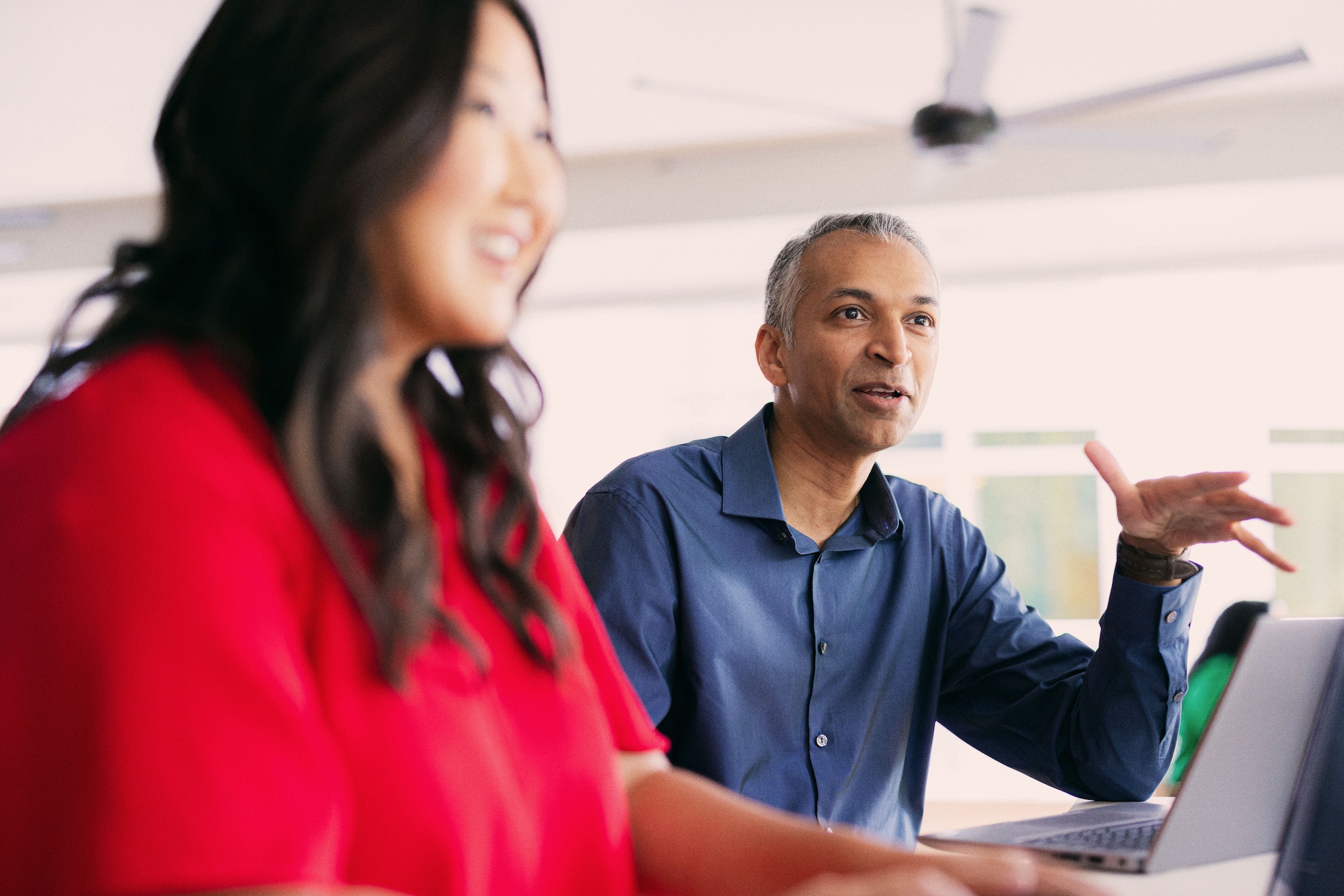 Two Cox employees engaged in conversation around their laptops