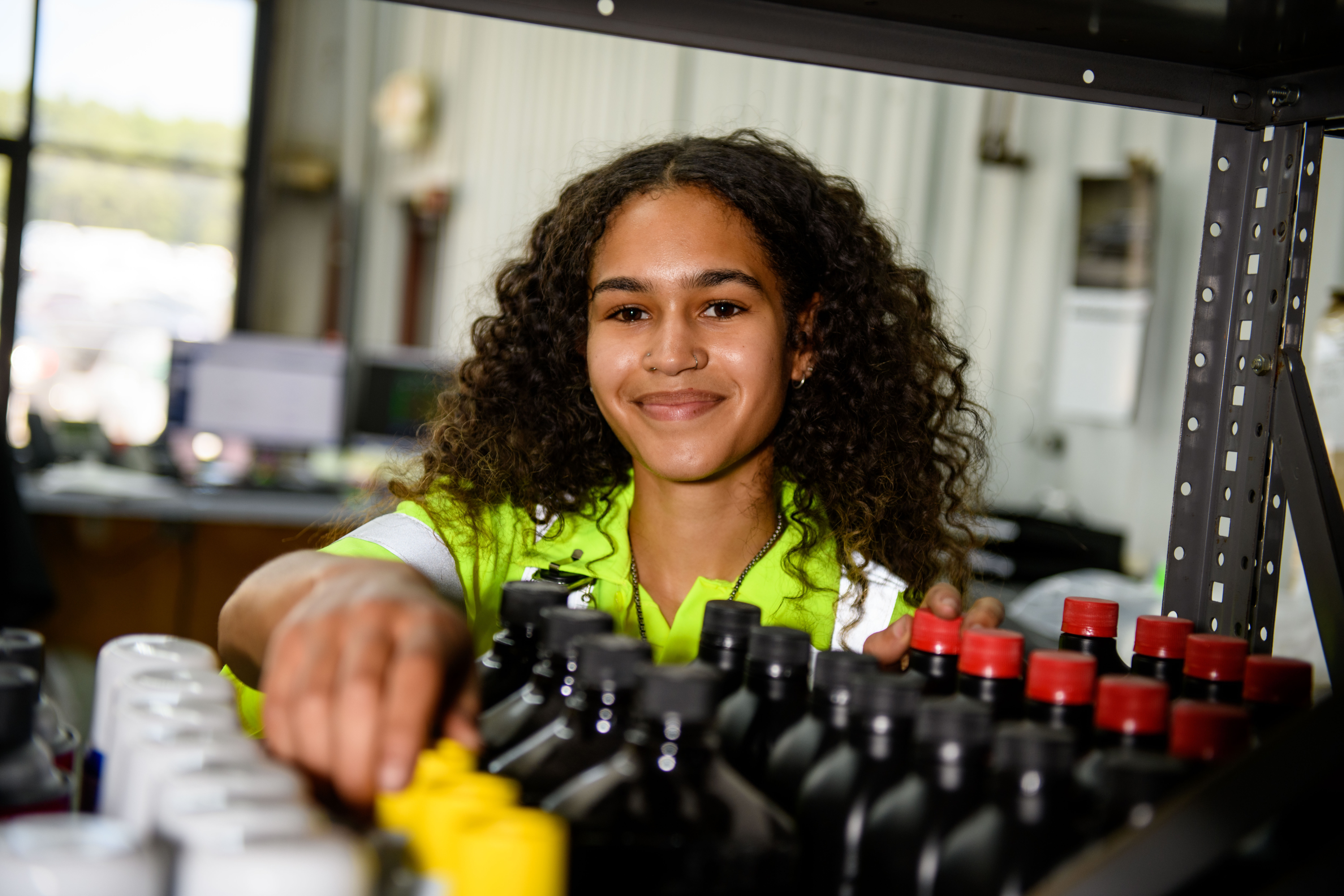 A young woman smiles as she stocks auto products.