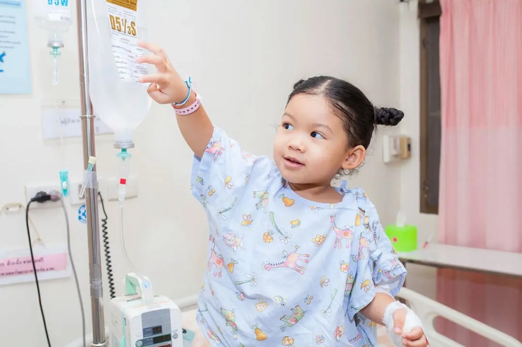 Young girl in a hospital gown investigating her medical equipment