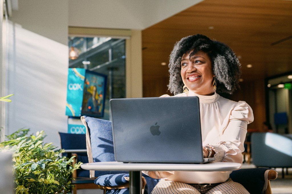 Cox employee sitting at a table working on her laptop