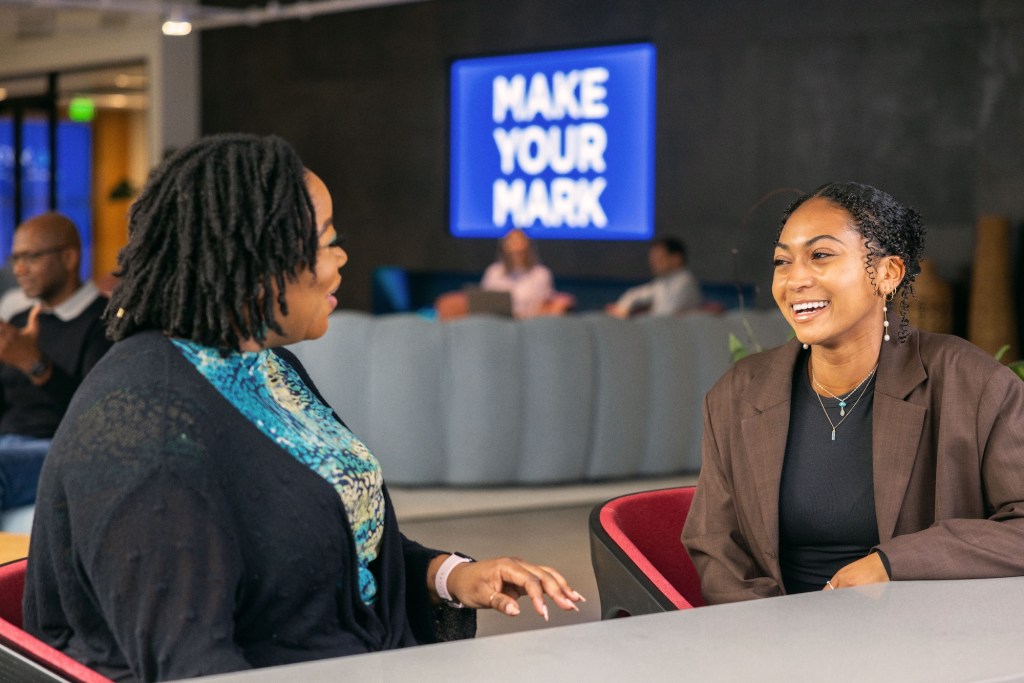 Two Cox employees chatting and laughing at a table