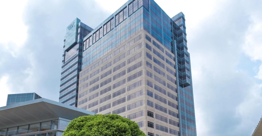 A tall metallic office building set against a blue sky.