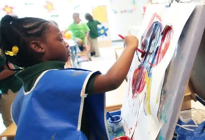 Young child painting at an easel.