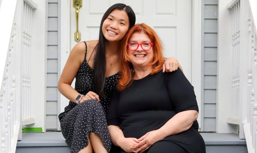 Two women sitting closely on the front steps of their house.