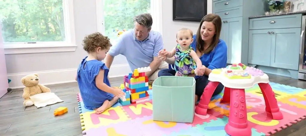 A family of four, including two small children, play with toys.