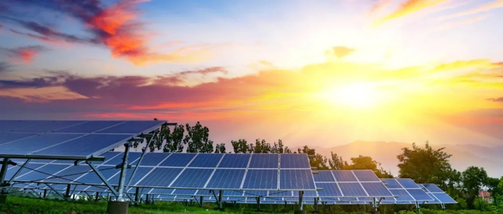 The sun sets behind solar panels