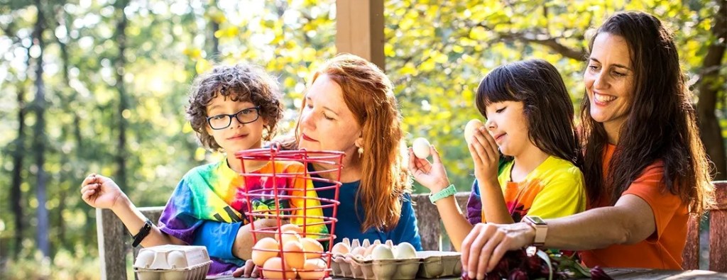 A woman and two children dye Easter eggs