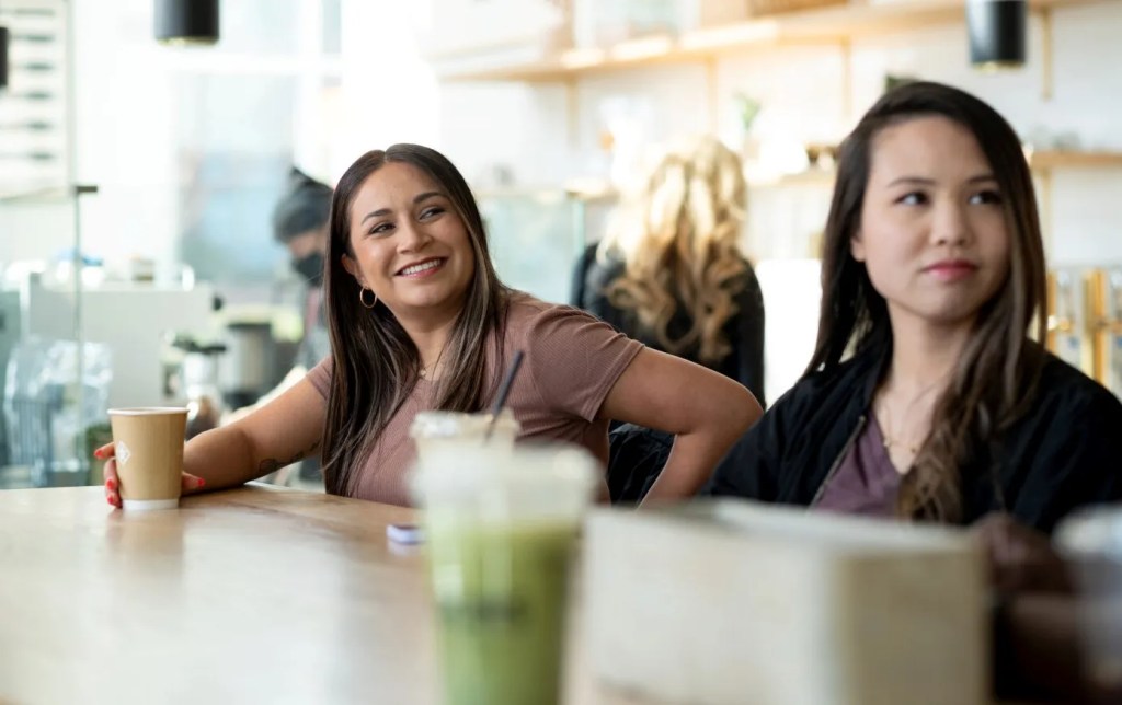 Two women sitting at a bar with coffees and smoothies.