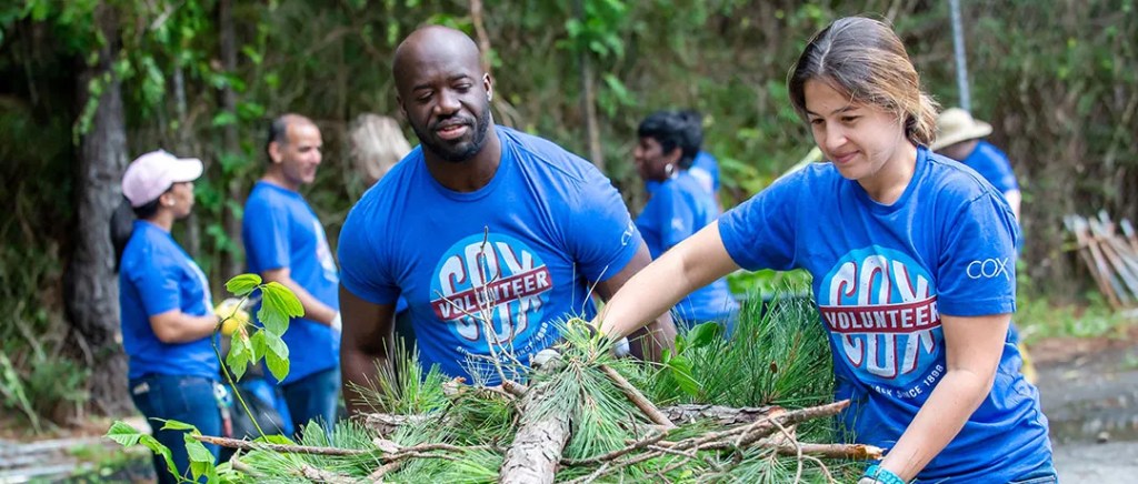 Two volunteers work together to move tree branches.